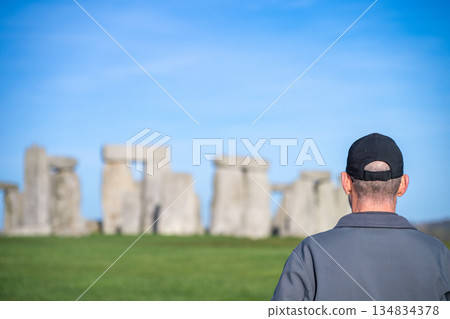 Selective focus on a man as he views ancient stone formation at Stonehenge in England during daytime with clear sky Selective focus on a man as he views ancient stone formation at Stonehenge in England during daytime with clear sky 134834378