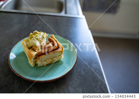 Pistachio cinnamon roll halves on an artisan plate in a home kitchen, top view. Natural light and simple setup show homemade dessert details. Concept of breakfast, pastry, comfort, homemade. 134834443
