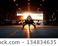 A military fighter jet stands majestically in a hangar, bathed in the warm glow of the setting sun 134834635