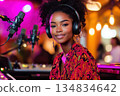 A young Black woman with headphones creates music in a recording studio, smiling at the camera 134834642