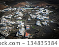 White buildings, town among volcanic black mountains and lava formations in Lanzarote, Canary Islands. 134835384