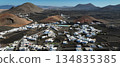 White buildings, town among volcanic black mountains and lava formations in Lanzarote, Canary Islands. 134835385