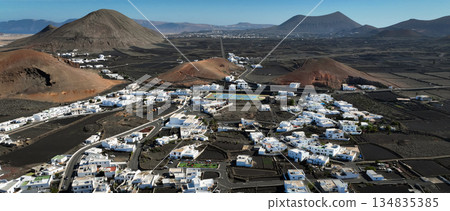 White buildings, town among volcanic black mountains and lava formations in Lanzarote, Canary Islands. White buildings, town among volcanic black mountains and lava formations in Lanzarote, Canary Islands. 134835385