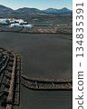 White buildings, town among volcanic black mountains and lava formations in Lanzarote, Canary Islands. 134835391
