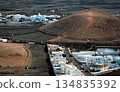 White buildings, town among volcanic black mountains and lava formations in Lanzarote, Canary Islands. 134835392