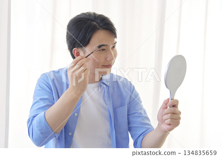 Man in his 20s drawing his eyebrows Man in his 20s drawing his eyebrows 134835659