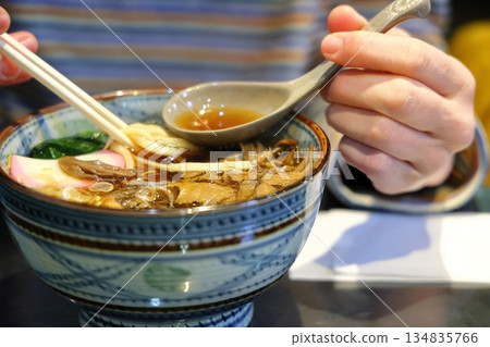 A woman eating warm udon noodles A woman eating warm udon noodles 134835766