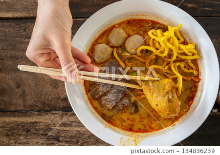 Someone try to eating Chicken Khao soi (Northern Thai Coconut Curry Noodle Soup). Khao soi is one of the most popular Thai dishes to eat in northern Thailand, especially in Chiang Mai and Chiang Rai. Someone try to eating Chicken Khao soi (Northern Thai Coconut Curry Noodle Soup). Khao soi is one of the most popular Thai dishes to eat in northern Thailand, especially in Chiang Mai and Chiang Rai. 134836239