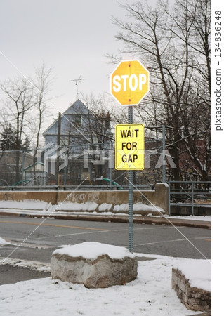 Road scene with a STOP sign and a caution sign on a snowy street corner 134836248