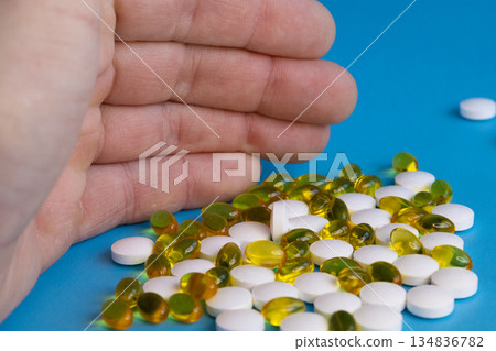 Hand holding assorted vitamin pills 134836782
