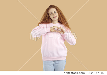 Happy beautiful young woman doing heart shaped gesture to show her support and gratitude Happy beautiful young woman doing heart shaped gesture to show her support and gratitude 134837102