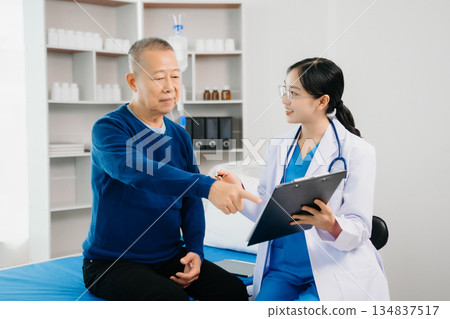 Doctor discussing treatment with Senior male patient talking and laughing sitting on examination bed in clinic or hospital Doctor discussing treatment with Senior male patient talking and laughing sitting on examination bed in clinic or hospital 134837517