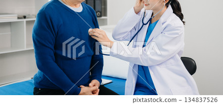 Doctor discussing treatment with Senior male patient talking and laughing sitting on examination bed in clinic or hospital 134837526