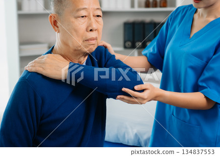 Asian physiotherapist helping male patient stretching arm during exercise correct with dumbbell in hand during training hand Asian physiotherapist helping male patient stretching arm during exercise correct with dumbbell in hand during training hand 134837553