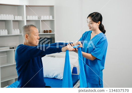 Asian physiotherapist helping elderly man patient stretching arm during exercise correct with dumbbell in hand during training hand with patient Back problems 134837570
