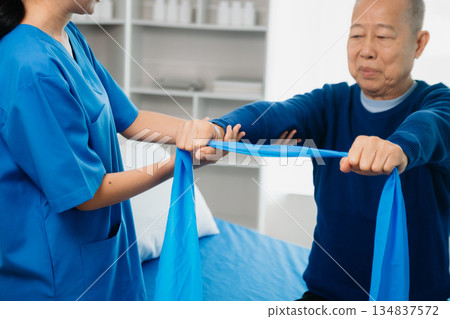 Asian physiotherapist helping elderly man patient stretching arm during exercise correct with dumbbell in hand during training hand with patient Back problems Asian physiotherapist helping elderly man patient stretching arm during exercise correct with dumbbell in hand during training hand with patient Back problems 134837572