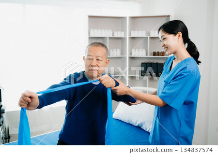 Asian physiotherapist helping elderly man patient stretching arm during exercise correct with dumbbell in hand during training hand with patient Back problems 134837574