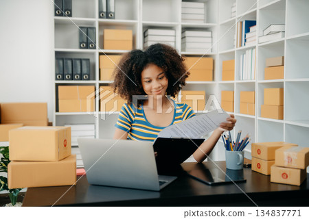 Startup small business SME, Entrepreneur owner African woman using smartphone or tablet taking receive and checking online purchase shopping order Startup small business SME, Entrepreneur owner African woman using smartphone or tablet taking receive and checking online purchase shopping order 134837771