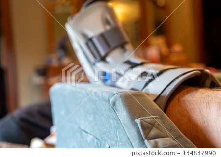 Elevated Foot in medical boot resting on a soft surface in a home setting during the day 134837990