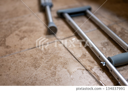 Crutches placed on wet floor in a building during the day after an accident or injury 134837991
