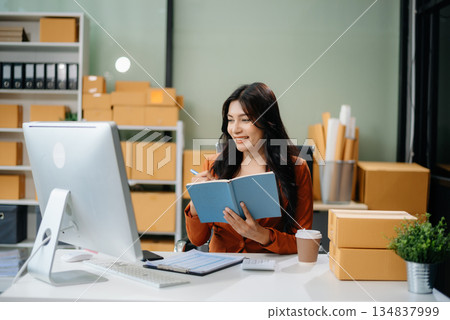 Businesswoman handling packaging and logistics in a modern workspace, managing e-commerce orders efficiently Businesswoman handling packaging and logistics in a modern workspace, managing e-commerce orders efficiently 134837999