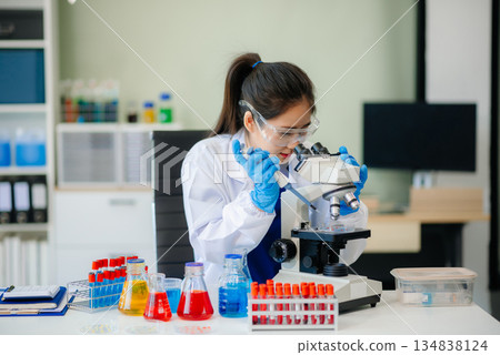 Discover a dedicated scientist conducting laboratory research, using pipettes, microscopes, and lab equipment. 134838124