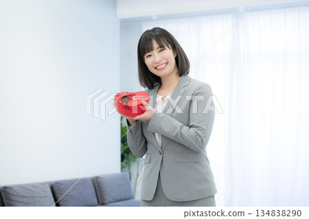 Businesswoman holding heart-shaped chocolates and presents. Image of customer satisfaction and gifts. Businesswoman holding heart-shaped chocolates and presents. Image of customer satisfaction and gifts. 134838290
