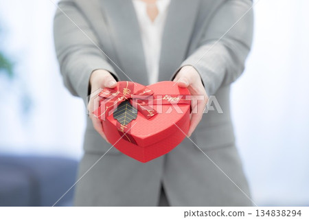 Businesswoman holding heart-shaped chocolates and presents. Image of customer satisfaction and gifts. No face. 134838294
