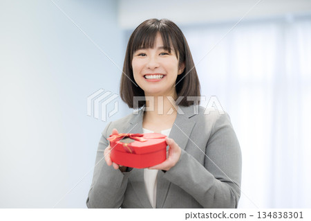 女商人手持心形巧克力和禮物。展現顧客滿意和禮物的畫面。 134838301