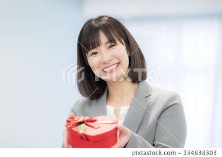 女商人手持心形巧克力和禮物。展現顧客滿意和禮物的畫面。 134838303