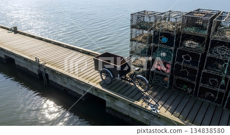 Aerial View Of Wooden Dock With Cargo Bicycle And Crab Traps Near Water Under Bright Sunlight 134838580