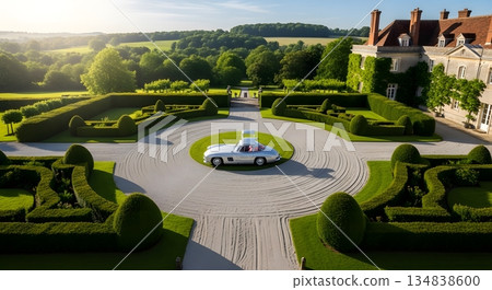 Classic Car on Circular Driveway in Front of Manor House with Formal Gardens Under Sunlight 134838600