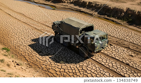 Military Truck Driving On Cracked Earth Under Bright Sunlight Creating Shadow 134838749