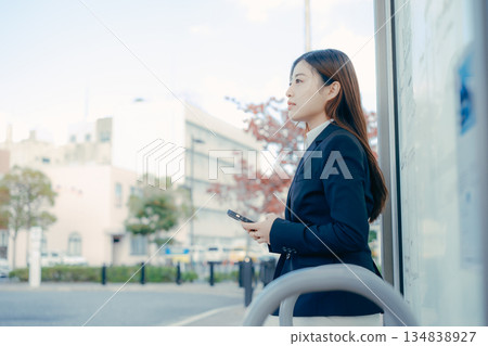 Japanese female university student thinking about job hunting at a bus stop Japanese female university student thinking about job hunting at a bus stop 134838927