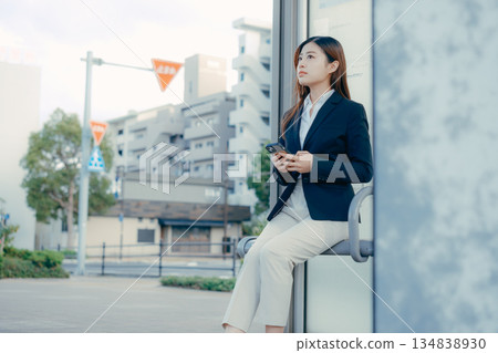 Japanese female university student thinking about job hunting at a bus stop Japanese female university student thinking about job hunting at a bus stop 134838930