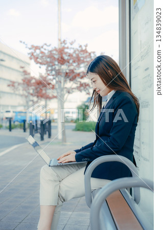 Japanese female university student using a laptop at the bus stop 134839023