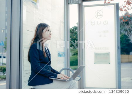 一名日本女大學生在公車站使用筆記型電腦 134839030