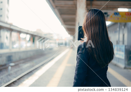 一名日本女大學生在車站月台上操作智慧型手機 134839124