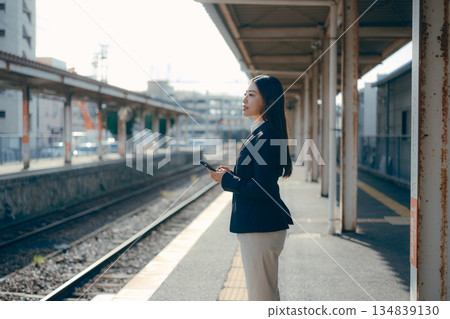 一名日本女大學生在車站月台上操作智慧型手機 一名日本女大學生在車站月台上操作智慧型手機 134839130