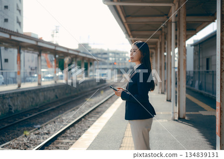 一名日本女大學生在車站月台上操作智慧型手機 一名日本女大學生在車站月台上操作智慧型手機 134839131