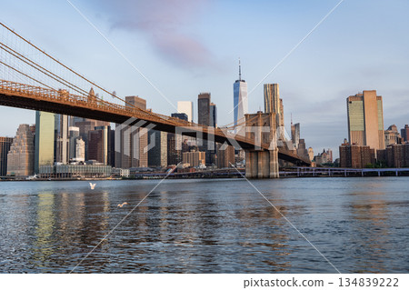 Brooklyn bridge to Manhattan on sunset. Urban architecture of New York city. Brooklyn bridge of New York city. Brooklyn landmark. Manhattan cityscape with skyscraper architecture Brooklyn bridge to Manhattan on sunset. Urban architecture of New York city. Brooklyn bridge of New York city. Brooklyn landmark. Manhattan cityscape with skyscraper architecture 134839222