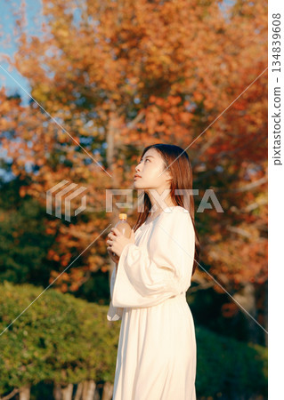 Japanese woman drinking tea in the autumn park Japanese woman drinking tea in the autumn park 134839608