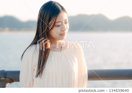 一位日本女子站在堤壩上,背景是大海。 一位日本女子站在堤壩上,背景是大海。 134839640
