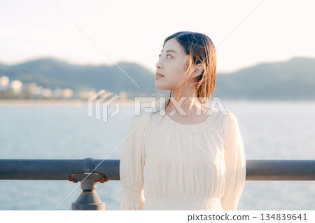 一位日本女子站在堤壩上，背景是大海。 134839641
