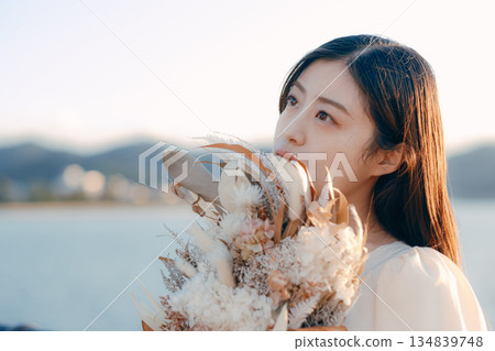 一位日本女子手捧乾花，站在海邊。 134839748
