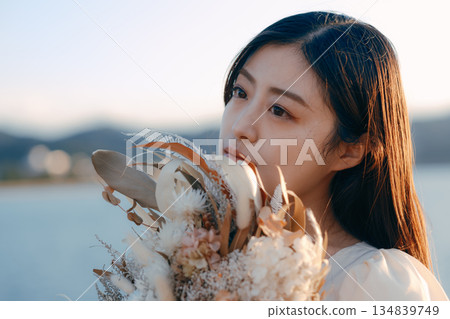 A Japanese woman standing with dried flowers in the background of the sea A Japanese woman standing with dried flowers in the background of the sea 134839749