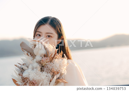 一位日本女子手捧乾花，站在海邊。 134839753