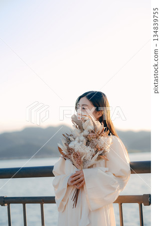 A Japanese woman standing with dried flowers in the background of the sea A Japanese woman standing with dried flowers in the background of the sea 134839755