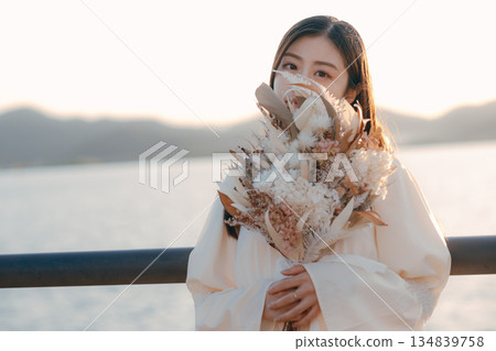 A Japanese woman standing with dried flowers in the background of the sea A Japanese woman standing with dried flowers in the background of the sea 134839758