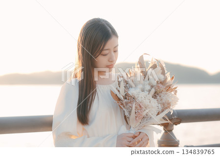 A Japanese woman standing with dried flowers in the background of the sea A Japanese woman standing with dried flowers in the background of the sea 134839765